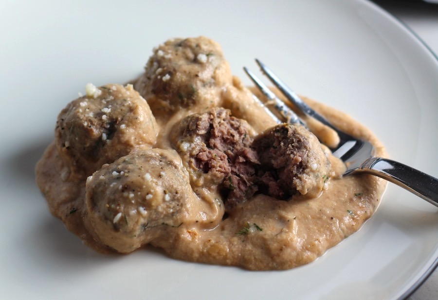 Meatballs in Cauliflower Dill Cream Sauce on plate with fork and skillet in background. The Meatballs are in a creamy cauliflower sauce with garlic, fresh dill, cream cheese, and tomato paste. #meatballs #swedishmeatballs #familydinner #easydinner #dinner #healthydinner