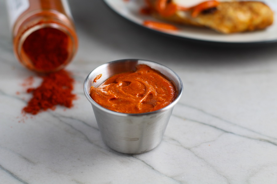 Hungarian Paprika Aioli in silver cup with Paprika spilling out of jar on counter for Hungarian Paprika Chicken.  The paprika gives beautiful color and a deep, peppery flavor. #chicken #easychicken #easydinner #dinner #healthydinner