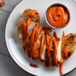 Hungarian Paprika Chicken sliced on plate with Paprika Aioli drizzled on top and fork dipping a bite. The paprika gives beautiful color and a deep, peppery flavor. #chicken #easychicken #easydinner #dinner #healthydinner