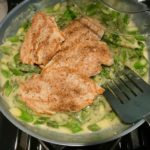 Chicken added to asparagus sauce in pan for Lemon Dill Sauce Chicken and Asparagus. It has chicken in a light and creamy sauce flavored with garlic, lemon and fresh dill. It's loaded with fresh asparagus. #springrecipes #dinner #easydinner #healthydinner #lemon #asparagus #chicken #glutenfree #easyrecipes