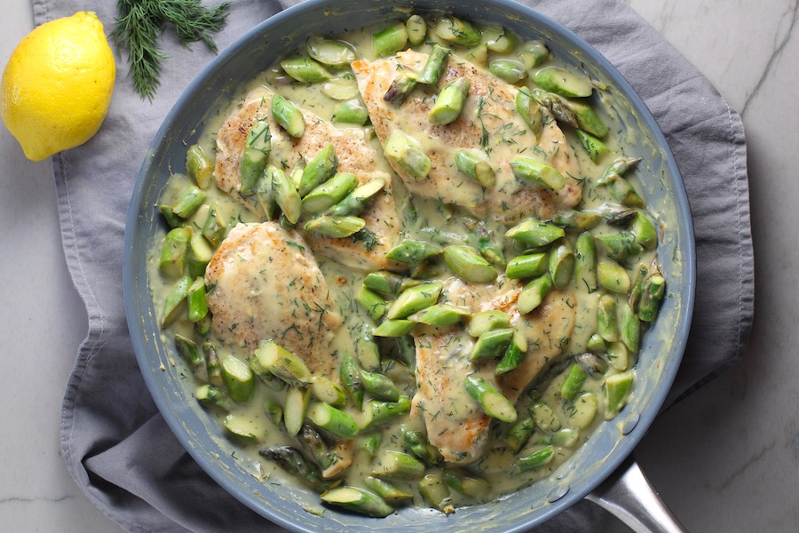 Cooked Lemon Dill Sauce Chicken and Asparagus in pan on stove. It has chicken in a light and creamy sauce flavored with garlic, lemon and fresh dill. It's loaded with fresh asparagus. #springrecipes #dinner #easydinner #healthydinner #lemon #asparagus #chicken #glutenfree #easyrecipes