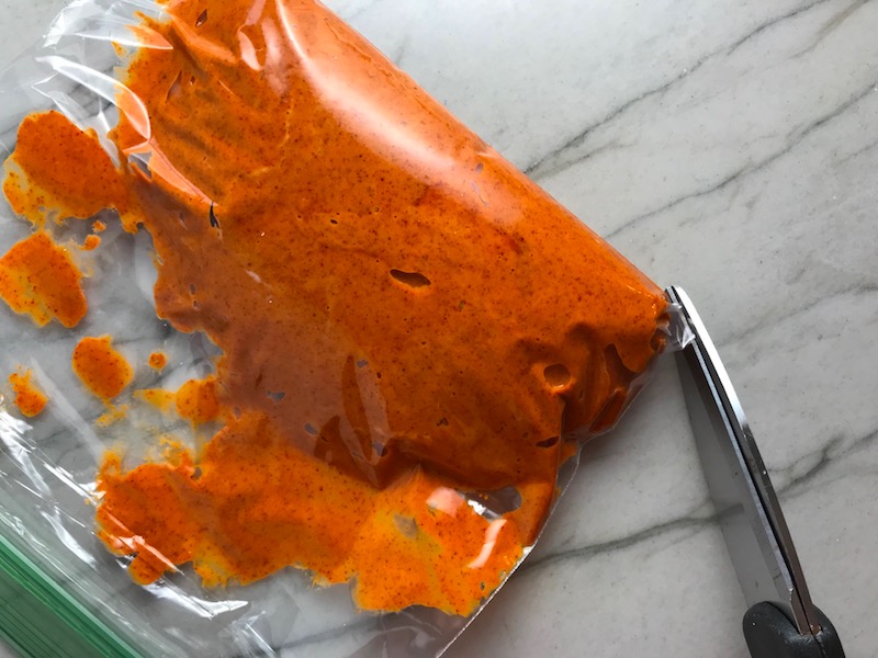 Scissors snipping corner of bag with Paprika Aioli for Hungarian Paprika Chicken. The paprika gives beautiful color and a deep, peppery flavor. #chicken #easychicken #easydinner #dinner #healthydinner