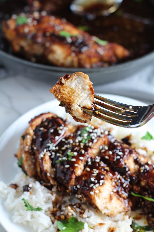 Bite of Sesame Sweet Chili Chicken on a fork over more sliced on a plate with rice. It is slightly sweet, tangy, savory, nutty, with a touch of heat. You can prepare it days ahead, it takes just minutes to prepare, minutes to cook, and everyone will love it!! #chicken #marinades #easydinner #easychicken #chickenrecipes #easysauces #healthydinner #healthyfood #healthyrecipes