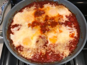 Skillet Eggs in Spicy Tomato Pepper Sauce with Manchego Cheese cooked in a skillet. With a smoky, spicy, thick, and luscious red pepper tomato sauce. #eggs #huevosrancheros #tomatosauce #easydinner #brunch #shakshuka