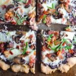 Flatbread cut into 4 pieces on a pan with a crispy gluten free crust, salty and briny Olive Tapenade, creamy mozzarella, earthy and meaty mushrooms, peppery pancetta, and fresh basil. #flatbread #pizza #olives #tapenade #mediterranean #easydinner #dinner
