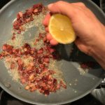 Hand squeezing half a lemon over cooked diced Pancetta in skillet for Pancetta, Parmesan, and Pepper Pasta. The Pancetta gives a salty and slightly peppery flavor, Parmesan cheese creates a nutty and creamy sauce, and the ground black pepper gives a peppery flavor that makes this pasta stand out. #pasta #easypasta #easydinner #dinner #italian #familydinner #onpotdinners #onepandinners #parmesan