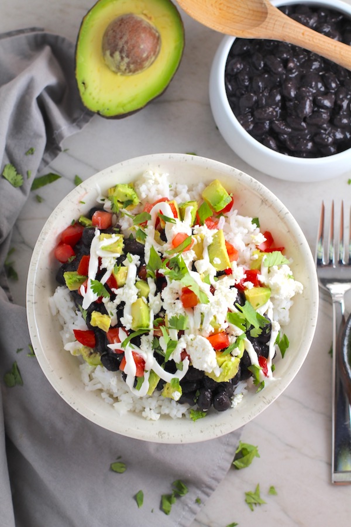 Black Bean Taco Bowl with rice, smoky black beans, avocado, salty Cotija cheese, sour cream, fresh tomato, and bright cilantro. This Black Bean Taco Bowl Bar lets everyone fills their bowl with any of the toppings they want! Perfect for kids.