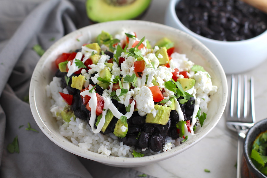 Black Bean Taco Bowl with rice, smoky black beans, avocado, salty Cotija cheese, sour cream, fresh tomato, and bright cilantro. This Black Bean Taco Bowl Bar lets everyone fills their bowl with any of the toppings they want! Perfect for kids. #tacos #tacobowls #healthyfood #dinner #healthydinner #familydinner #kidsdinner #blackbeans #vegetarian