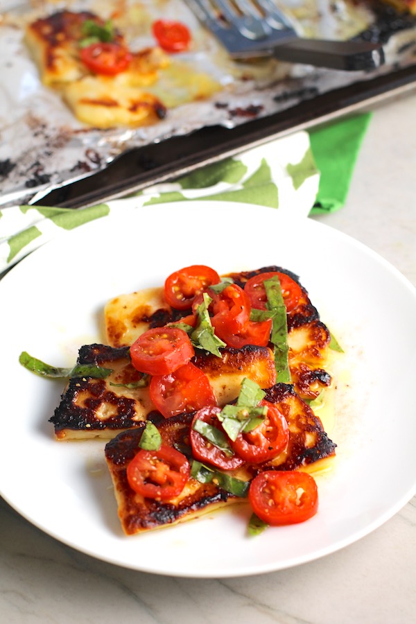 Grilled Halloumi Cheese & Tomato Salad on plate.  It's insanely delicious! Grilled Halloumi has a strong savory and salty flavor that is slightly creamy and incredibly addictive. Paired with my simple Tomato and Basil salad, each bite is simply heaven. #halloumi #appetizers #salads #grilling #summerfood