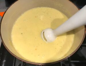 Immersion blender blending corn soup in pot for Chilled Golden Corn Soup with Turmeric.  Scallions on top for garnish. It's thick, creamy, silky and delicious.  The entire family will love this easy stovetop corn soup! #summerfood #cornsoup #corn #vegetarian #vegetablerecipes #sides