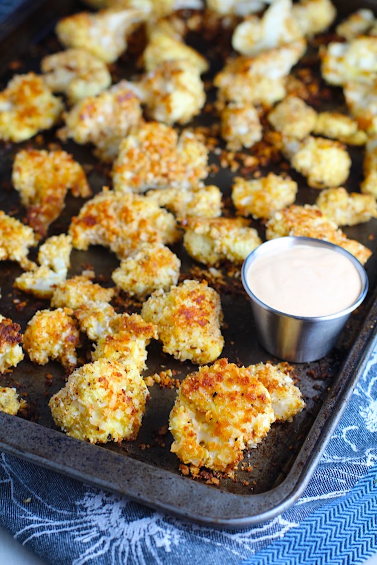 BReaded Cauliflower Recipe on pan.  They have a slightly sweet and salty crunch outside from the shredded coconut and panko mixture.  The inside is soft and creamy. 