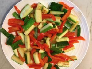 Red Peppers and Zucchini on plate for Family Coconut Curry. The sauce has onion, coconut milk, ginger, garlic, and warm Indian Curry spices.