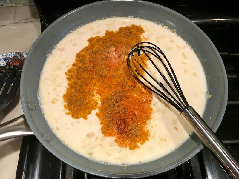 Mixing curry seasoning in coconut milk for Family Coconut Curry. The sauce has onion, coconut milk, ginger, garlic, and warm Indian Curry spices.