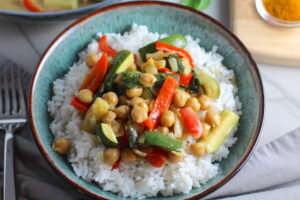 Family Chickpea Coconut Curry over rice in a bowl with red bell pepper, zucchini, onion, coconut milk, and warm Indian Curry spices.