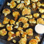 Baked Coconut Crispy Cauliflower Bites on pan.  They have a slightly sweet and salty crunch outside from the shredded coconut and panko mixture.  The inside is soft and creamy. 