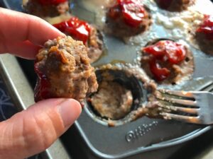 Hand holding cooked Mini Meatloaf Muffins They have only 5 simple ingredients, cook in 30 minutes, and are gluten free.