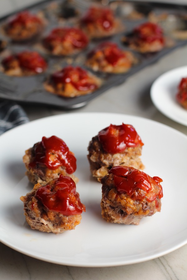 Mini Meatloaf Muffins on a plate. They have only 5 simple ingredients, cook in 30 minutes, and are gluten free. Parmesan gives salty and nutty flavor.  Ketchup on top cooks down into a thick, deep-flavored tangy, salty, and sweet glaze.