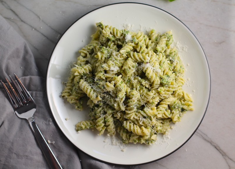 Broccoli Pesto Pasta on a plate with parmesan on top. It's delicious AND good for you!  It has all of the classic pesto flavors from garlic, basil, parmesan cheese, and pine nuts.  But the flavor is a bit more mellow by adding broccoli! #broccolirecipes #pesto #pasta #easydinner #dinnerideas #familydinner
