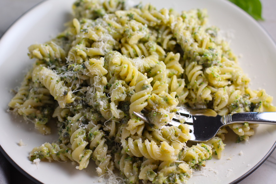Broccoli Pesto Pasta on a plate with fork in pasta. It's delicious AND good for you!  It has all of the classic pesto flavors from garlic, basil, parmesan cheese, and pine nuts.  But the flavor is a bit more mellow by adding broccoli! #broccolirecipes #pesto #pasta #easydinner #dinnerideas #familydinner