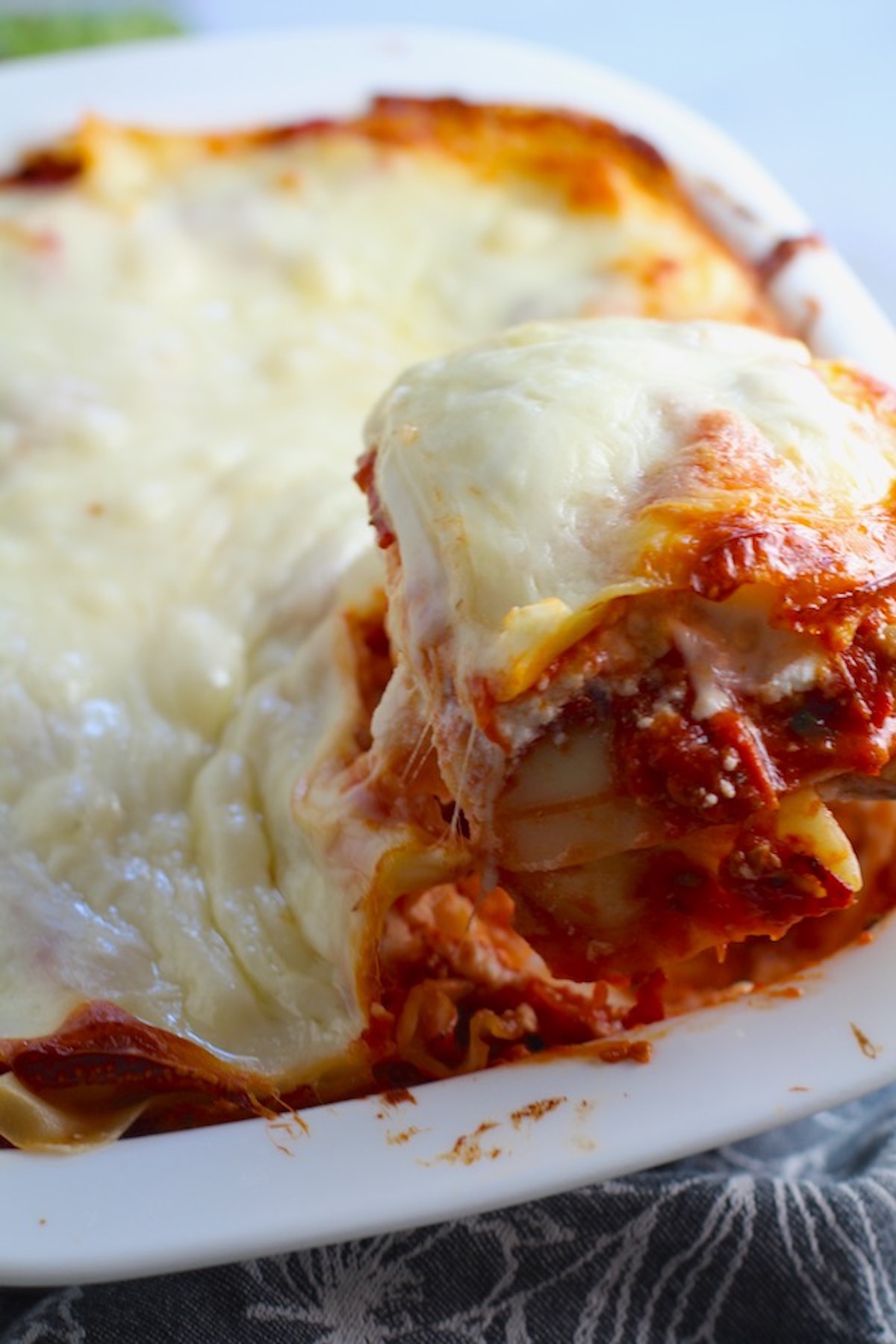Scooping a piece of Chicken lasagna from the dish. This Italian Sausage Lasagne Recipe is the stuff that dreams are made of.  Layers of pasta, creamy ricotta, salty chewy mozzarella, salty and hearty Italian Sausage, and sweet and tangy tomato sauce.
