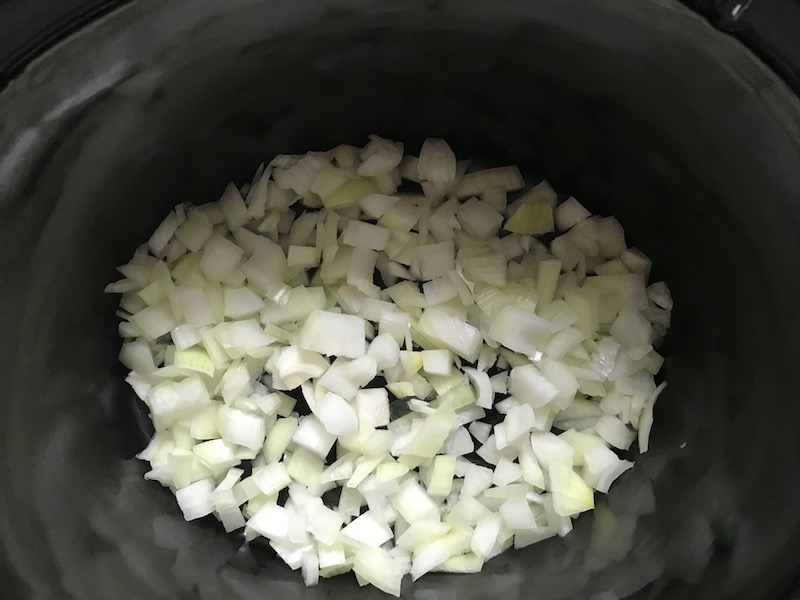 Diced onion in Slow Cooker insert for Smoky Pulled Beef Brisket.  It's smokey, savory, tender, moist, and full of flavor. In a delicious sauce, it goes great on a sandwich, over polenta, on rice, or potatoes. #slowcooker #crockpot #brisket #beefbrisket #pulledbeef #pulledpork