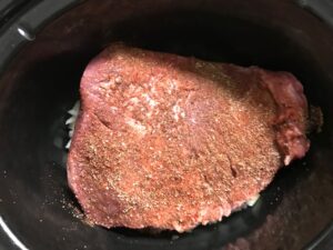 Spiced rubbed raw brisket in Slow Cooker insert for Smoky Pulled Beef Brisket.  It's smokey, savory, tender, moist, and full of flavor. In a delicious sauce, it goes great on a sandwich, over polenta, on rice, or potatoes. #slowcooker #crockpot #brisket #beefbrisket #pulledbeef #pulledpork