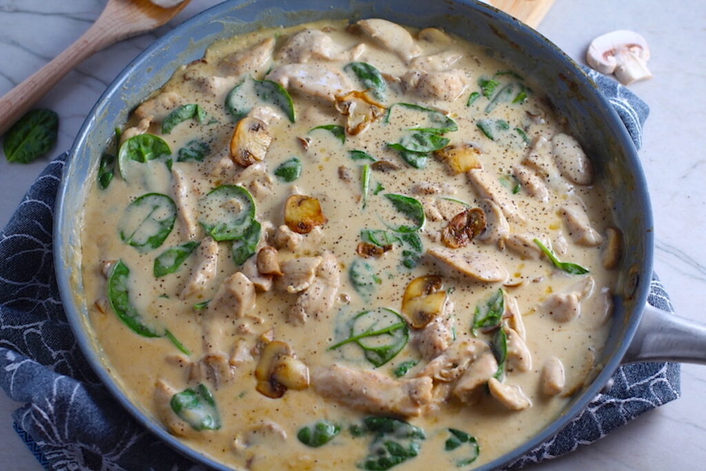 Chicken Mushroom Stroganoff in a skillet with mushrooms and spinach. It has a thick, creamy, savory mushroom sauce with a touch of tangy sour cream.