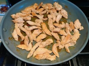 Cooked chicken strips in pan for Chicken Stroganoff with mushrooms, and spinach.  It has a thick, creamy, savory mushroom sauce with a touch of tangy sour cream. #chickendinners #chickenrecipes #familydinners #dinnerideas