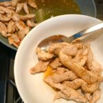 Spoon removing cooked chicken from pan for Chicken Stroganoff with mushrooms, and spinach. It has a thick, creamy, savory mushroom sauce with a touch of tangy sour cream. #chickendinners #chickenrecipes #familydinners #dinnerideas