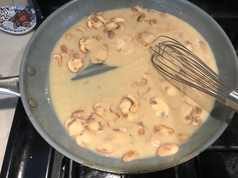 Thickened mushroom sauce in skillet for Chicken Stroganoff with mushrooms, and spinach.  It has a thick, creamy, savory mushroom sauce with a touch of tangy sour cream. #chickendinners #chickenrecipes #familydinners #dinnerideas