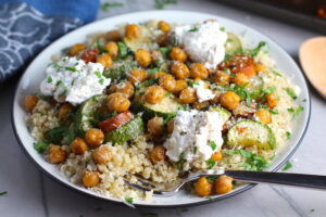 Mediterranean SHEET PAN DINNER on a plate with chicken sausage, parmesan zucchini. and crispy chickpeas over quinoa with dollops of seasoned Ricotta. #sheetpandinner #chickpeas