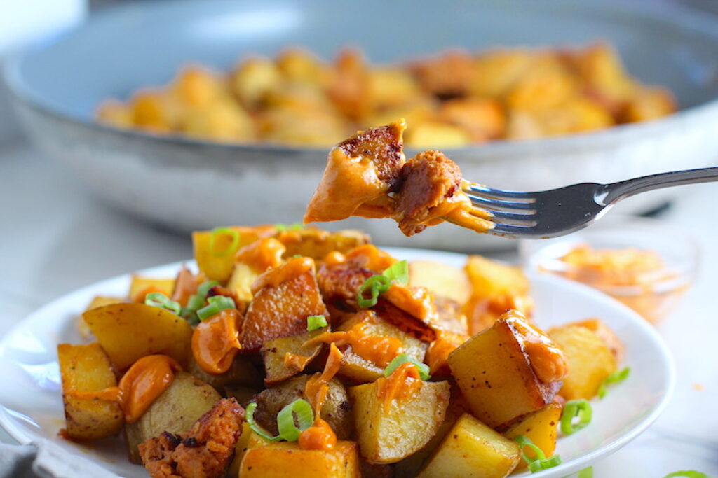 Patatas Bravas with chorizo on a plate with chorizo and creamy Paprika aioli drizzled over top. This Patatas Bravas Recipe, or Spicy Potatoes, is easy, indulgent, and utterly delicious! 