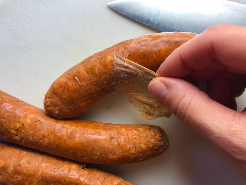 Peeling casing from Chorizo for Slow Cooker Egg Casserole with Chorizo, Potatoes and both cheddar and manchego cheeses. IT COOKS WHILE YOU SLEEP! #eggs #eggcasseroles #eggrecipes #breakfastideas #holidayrecipes