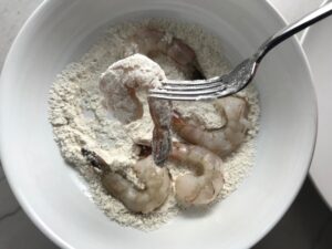 Raw shrimp in flour in a bowl for the Orange Brown Butter Shrimp Pasta Recipe.  It has a silky sauce that's buttery, nutty, and slightly sweet! #shrimprecipes #shrimppasta #easydinners #dinnerideas 
