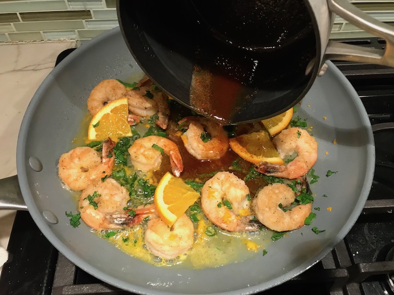 Adding brown butter to shrimp in skillet for the Orange Brown Butter Shrimp Pasta Recipe. #shrimprecipes #shrimppasta #easydinners #dinnerideas 