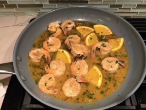 Shrimp with orange sauce in skillet for the Orange Brown Butter Shrimp Pasta Recipe. #shrimprecipes #shrimppasta #easydinners #dinnerideas 