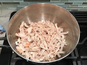 Shredded Chicken in pot for Chicken Taquitos. Corn tortillas are filled with smoky taco seasoned shredded chicken, and creamy cheddar cheese.  #dinnerideas #familydinner #chickenrecipes #chickendinner #tacos #taquitos