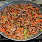 Beef filling in pan for Cottage Pie recipe. It has Spanish Chorizo and ground beef cooked in a rich and savory gravy with veggies and herbs.  Creamy mashed potatoes sit on top with manchego, parmesan, and garlic. #dinnerideas #cottagepie #shepherdspie