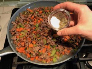 Beef filling in pan for Cottage Pie recipe.  It has Spanish Chorizo and ground beef cooked in a rich and savory gravy with veggies and herbs.  Creamy mashed potatoes sit on top with manchego, parmesan, and garlic. #dinnerideas #cottagepie #shepherdspie