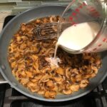 Adding slurry to cooked sliced Mushrooms in skillet for this Heavenly Mushroom Sauce Recipe. #vegetarian #healthydinner #dinnerideas #mushrooms