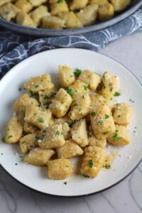 Gnocchi on plate with parmesan and parsley. Cauliflower Gnocchi are soft, silky, buttery, and melt-in-your-mouth! Made with cauliflower, they're a healthier version to traditional gnocchi! Add my simple Garlic Butter Sauce or Tomato Sauce and they are heaven.  #dinnerideas #gnocchi #cauliflower