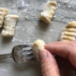 Rolling gnocchi on fork on for cauliflower gnocchi. These Gnocchi are soft, silky, buttery, and melt-in-your-mouth! Made with cauliflower, they're a healthier version to traditional gnocchi! Add my simple Garlic Butter Sauce or Tomato Sauce and they are heaven.  #dinnerideas #gnocchi #cauliflower