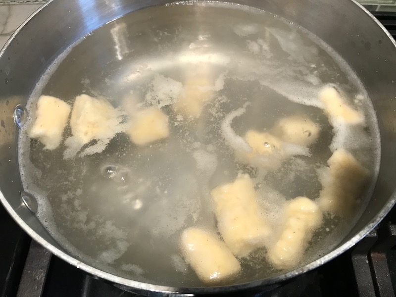 Cauliflower gnocchi cooking in boiling water.  These Gnocchi are soft, silky, buttery, and melt-in-your-mouth! Made with cauliflower, they're a healthier version to traditional gnocchi! Add my simple Garlic Butter Sauce or Tomato Sauce and they are heaven.  #dinnerideas #gnocchi #cauliflower