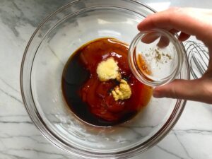 Hand adding ingredients to bowl for Chinese BBQ Sauce for Pork Tenderloin.  It's sweet, tangy, salty, and all together lick-your-fingers delicious!  It's also easy to make!  #chinesebbqsauce #bbq #bbqsauce