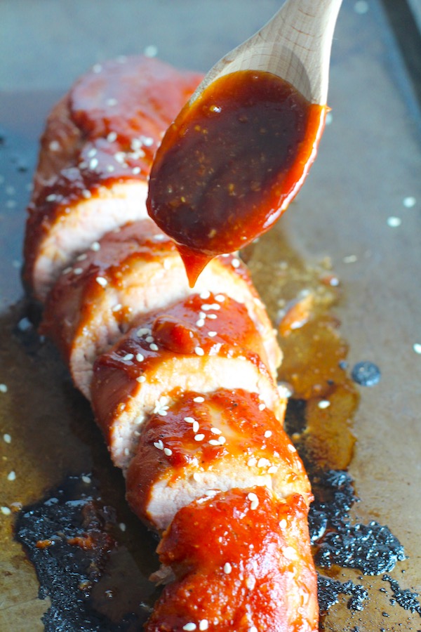 Chinese BBQ Pork Tenderloin sliced on board with sesame seeds and cup of sauce. It's sweet, tangy, salty, nutty, and all together lick-your-fingers delicious! It's also easy to make! Marinade ahead and then roast in the oven.