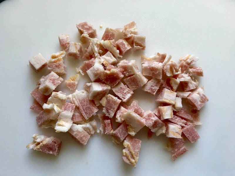 Raw bacon diced for Bacon Mac and Cheese. It has a creamy and cheesy sauce with a touch of smokiness from the bacon, coats each piece of pasta.  On top, crispy crunchy, indulgent bacon fat cracker crumbs!