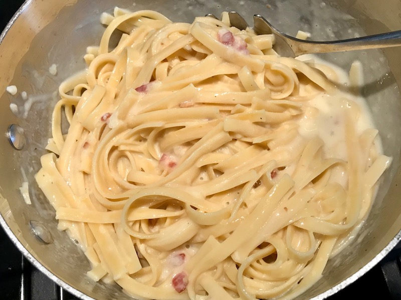 Mixing fettuccine into cheese sauce for Bacon Mac and Cheese. It has a creamy and cheesy sauce with a touch of smokiness from the bacon, coats each piece of pasta.  On top, crispy crunchy, indulgent bacon fat cracker crumbs!
