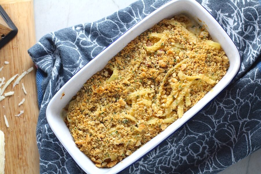 Bacon Mac and Cheese in baking dish. It has a creamy and cheesy sauce with a touch of smokiness from the bacon, coats each piece of pasta.  On top, crispy crunchy, indulgent bacon fat cracker crumbs!