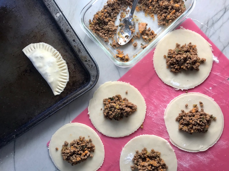 Making Ground Beef Empanadas - crust rounds with filling in center, beef filling in dish, and empanada on a pan. Flaky, buttery pastry on the outside with a savory, smokey, salty ground beef filling.
