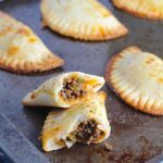 Ground Beef Empanadas on a pan. Flaky, buttery pastry on the outside with a savory, smokey, salty ground beef filling.